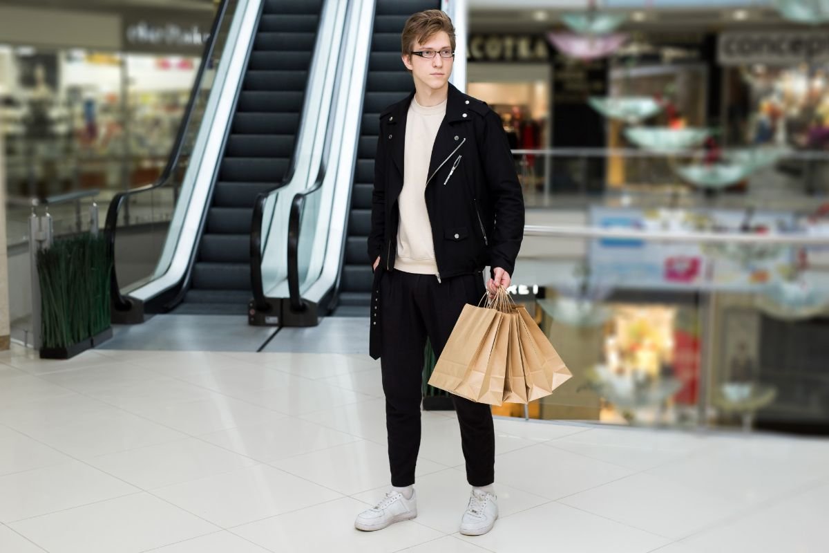 garoto com sacolas de compras no shopping